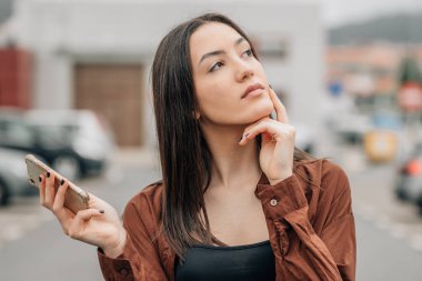 Düşünce ya da şüphe ifadesi olan cep telefonu olan kız