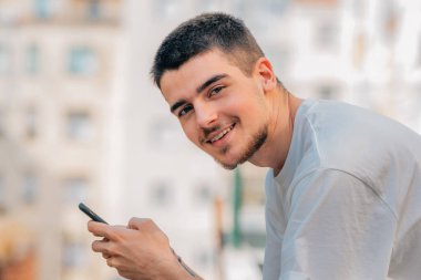 Şehirde cep telefonu ve cep telefonu olan genç bir adam.
