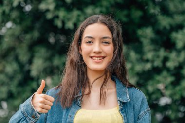 Telefonu olan kız mutlu bir şekilde gülümsüyor.