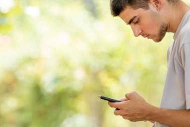 Profildeki genç adam kopyalama alanı olan cep telefonuna bakıyor