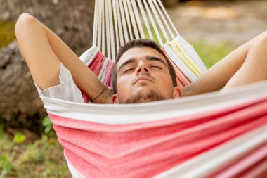 Genç adam yazın hamakta uyuyor.