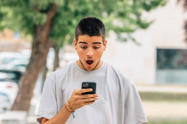 Choqué Jeune Homme Dans Rue Regardant Téléphone Mobile Smartphone — Photo