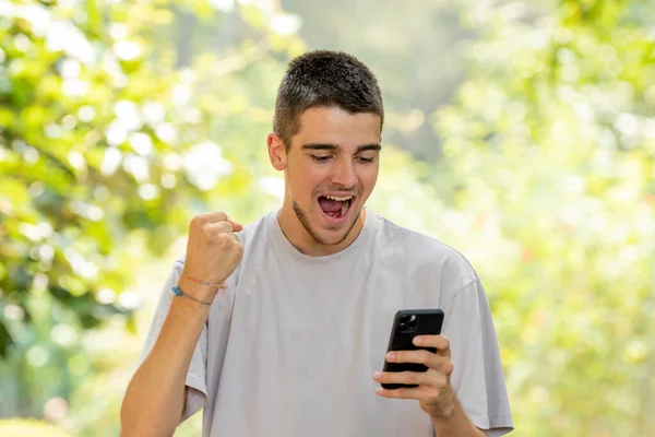 Aufgeregter Junger Mann Feiert Mit Blick Auf Handy — Stockfoto