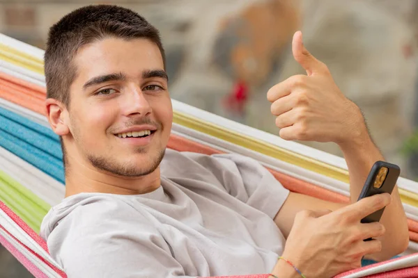 Relajado Hombre Joven Hamaca Con Teléfono Móvil Signo Satisfacción Bien — Foto de Stock