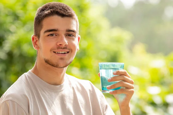 屋外で水を飲んでいる若い男は — ストック写真