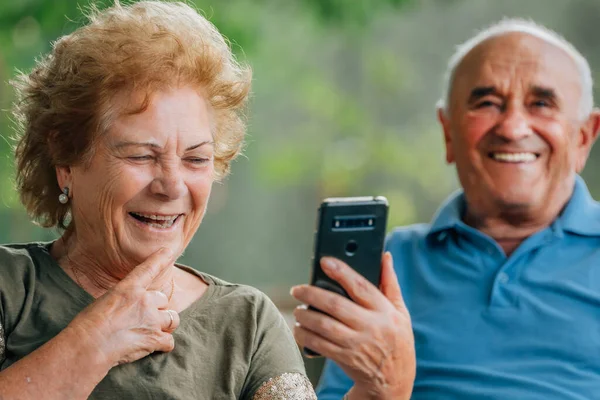 上了年纪的夫妇用手机或智能手机笑得开心 — 图库照片