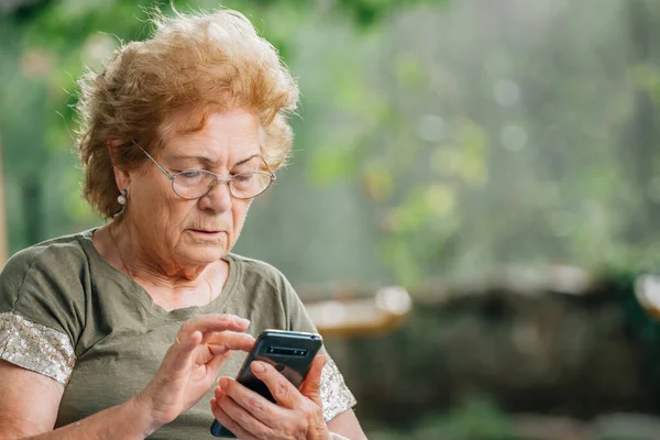 使用智能手机或带有复制空间的手机的老年妇女 — 图库照片