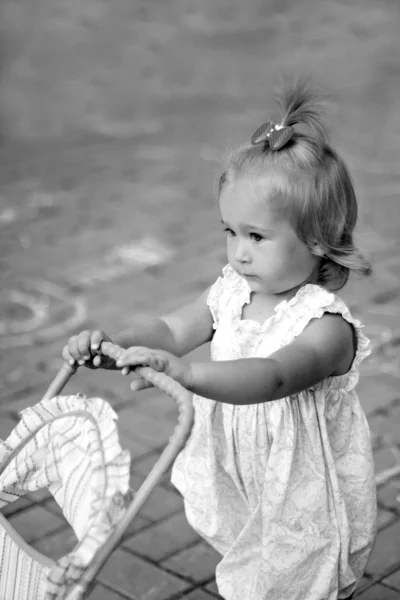 Meisje met speelgoed pram — Stockfoto