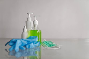 Beyaz arka planda bir dezenfeksiyon seti. Eldiven, maske, dezenfektan.
