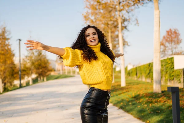 Ayrı el kıvırcık esmer, parlak kazaklı, mutlu bir şekilde gülümsüyor.