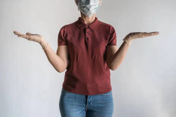 Onherkenbare volwassen vrouw met medisch masker houdt onzichtbaar in haar armen op witte achtergrond, gebaar niet weten — Stockfoto