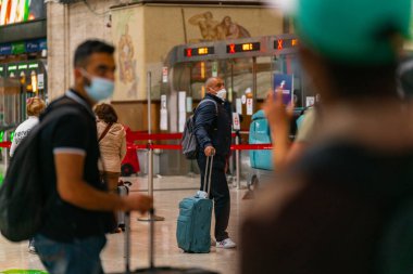 4.10.2021 Milan, İtalya - Milano Merkez Tren İstasyonu. Valizli insanlar tren istasyonunda tren bekliyor.