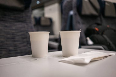 Trendeki masanın üzerinde tek kullanımlık kahve ve tahta sopa olan 2 beyaz kağıt bardak.