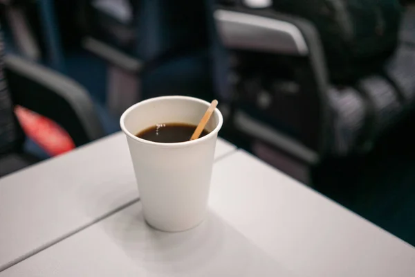 Copo descartável de papel branco com café e pau de madeira na mesa do trem — Fotografia de Stock