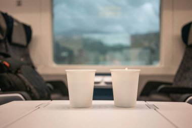 Trendeki bir pencerenin arkasında duran iki adet tek kullanımlık kağıt bardak. Avrupa 'da seyahat