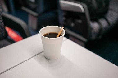 Trendeki bir masanın üzerinde tek kullanımlık beyaz bir cam duruyor. Avrupa 'da seyahat, tek kullanımlık sofra takımı