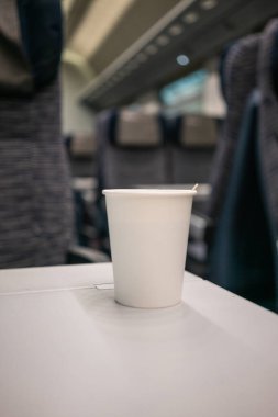 Trende masanın üzerinde tek kullanımlık beyaz bir kahve fincanı var. Avrupa 'da hızlı seyahat. Trenle seyahat et..