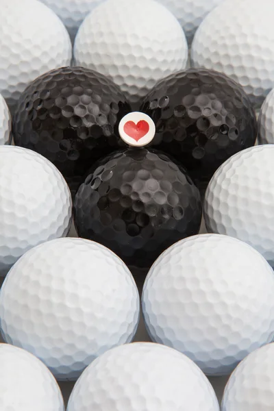 Witte en zwarte golfballen en houten tee — Stockfoto