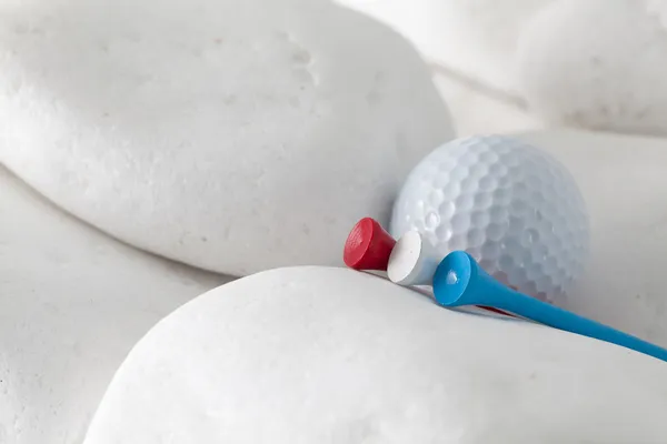 Pelota de golf y tees entre piedras blancas —  Fotos de Stock