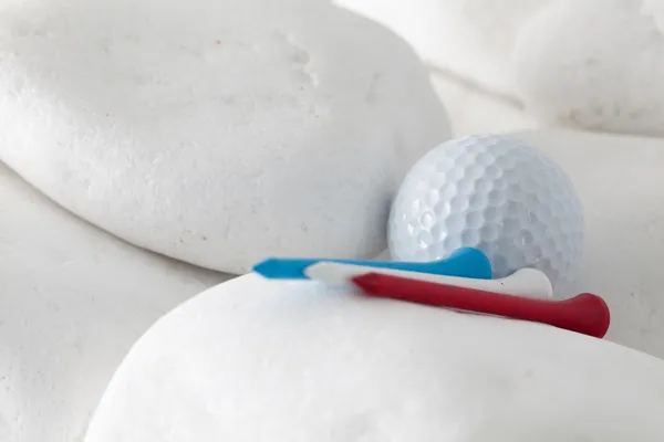 Golf ball and tees between white stones — Stock Photo, Image