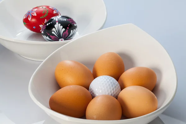 Taças brancas, ovos de Páscoa e bolas de golfe — Fotografia de Stock