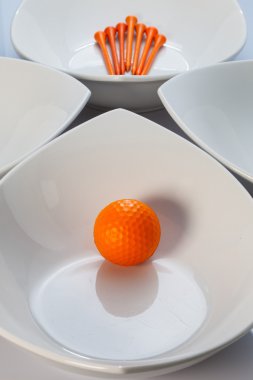 Beyaz seramik kaseler ve turuncu golf topu