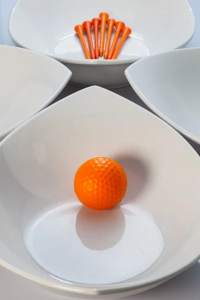 Weiße Keramikschalen und orangefarbener Golfball — Stockfoto