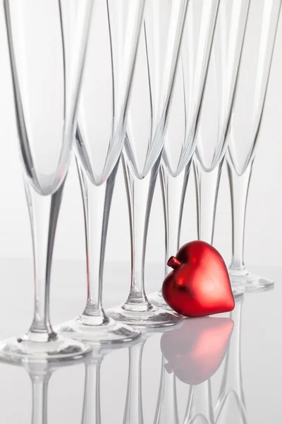 Sei bicchieri di champagne e cuore rosso su un tavolo di vetro — Foto Stock