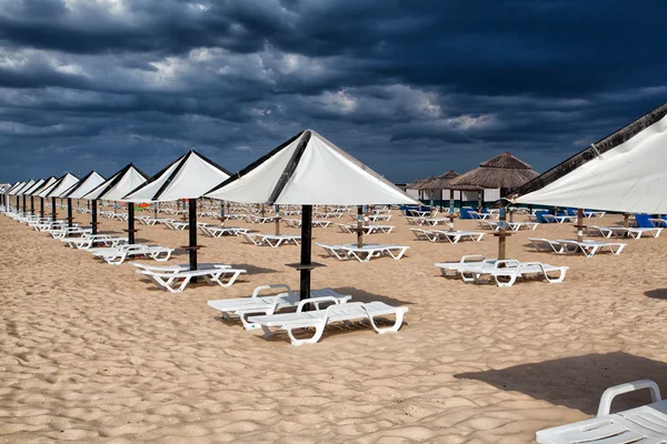 Különböző napernyőkkel és napozóágyakkal, tavira üres strandon — Stock Fotó
