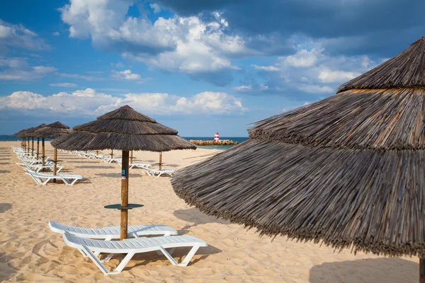 Különböző napernyőkkel és napozóágyakkal, tavira üres strandon — Stock Fotó