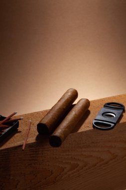 Siesta. Ahşap kirişte iki puro ve kibrit. Kahverengi arka plan..