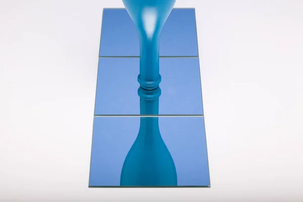镜面图像与反光蓝色瓶子在蓝色镜面 葡萄酒产品的概念 — 图库照片
