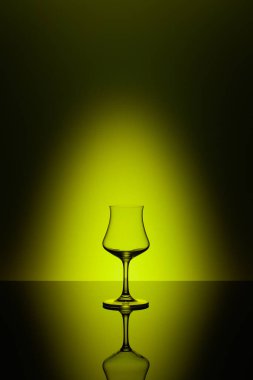 Rum tasting glass on the glass table and yellow background