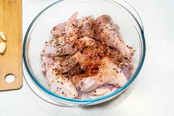 Кусочки разрезанной курицы с перцем и солью в стеклянной миске. — стоковое фото