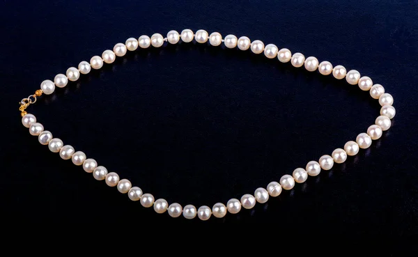 Pearl necklace on a dark blue leatherette background. — Stock Photo, Image