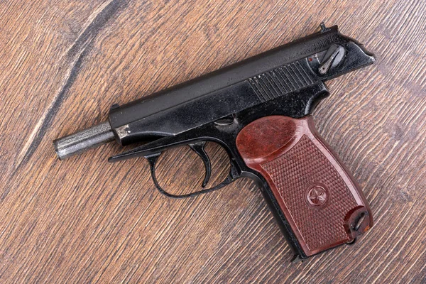 Makarov sisteminin eski tabancasının üst görüntüsü. Ahşap arka planda bir tabanca. Kapat..