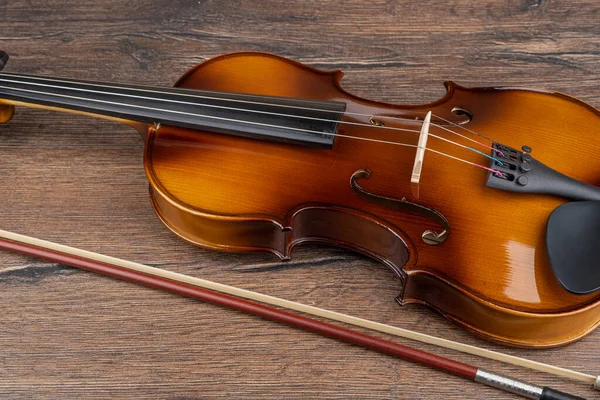 Part of a violin on a wooden background with a bow. — Stockfoto