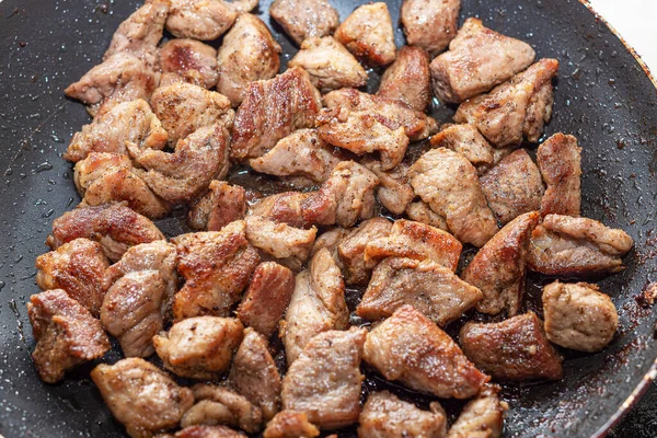 La viande de porc est frite dans une poêle. Des gouttes d'huile dans une poêle. — Photo