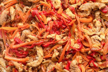 Domuz etinin tamamı biber, havuç ve soğanla dolu bir tavada pişirilir. Kapat..