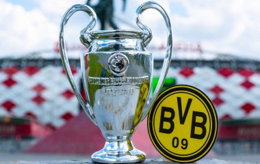 14 Haziran 2021 Dortmund, Almanya. Borussia Dortmund futbol kulübü ve UEFA Şampiyonlar Ligi Kupası 'nın amblemi modern bir stadyumun arka planına karşıdır..