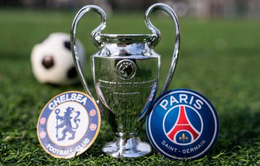 16 Nisan 2021 Moskova, Rusya. UEFA Şampiyonlar Ligi Kupası ve çimlerin üzerindeki yeşil çimlerde bulunan Paris Saint-Germain F. C. ve Chelsea F. C. London futbol kulüplerinin amblemleri..