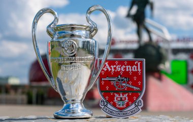 14 Haziran 2021 Londra, İngiltere. Arsenal F.C. Futbol kulübü amblemi ve UEFA Şampiyonlar Ligi Kupası modern bir stadyumun arka planına karşı..