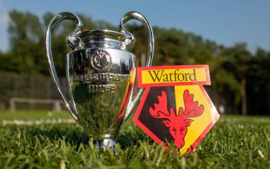 30 Ağustos 2021, Watford, İngiltere. Watford F.C. Futbol kulübü amblemi ve yeşil bir alanda UEFA Şampiyonlar Ligi Kupası.