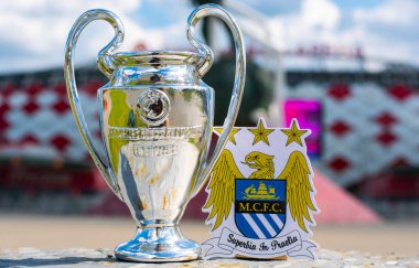14 Haziran 2021 Manchester, İngiltere. Manchester City futbol kulübünün amblemi ve UEFA Şampiyonlar Ligi Kupası modern bir stadyumun arka planına karşı..