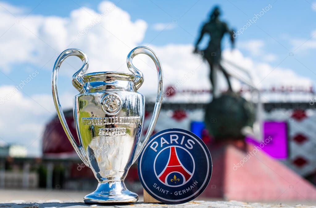 June 14, 2021 Paris, France. The emblem of the football club Paris Saint-Germain F.C. and the UEFA Champions League Cup against the backdrop of a modern stadium.