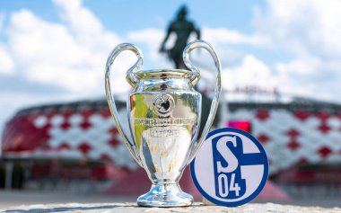 14 Haziran 2021, Gelsenkirchen, Almanya. FC Schalke 04 futbol kulübü ve UEFA Şampiyonlar Ligi Kupası 'nın amblemi modern bir stadyumun arka planına karşıdır..