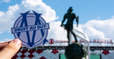 14 Haziran 2021, Marsilya, Fransa. Futbol kulübü Olympique de Marsilya 'nın amblemi modern stadyumun arka planına karşıdır..
