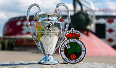 14 Haziran 2021, Santander, İspanya. Racing de Santander futbol kulübü ve UEFA Şampiyonlar Ligi Kupası 'nın amblemi modern bir stadyumun arka planına karşıdır..