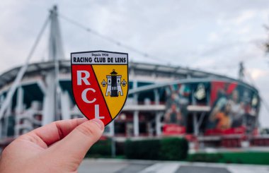 30 Ağustos 2021, Lens, Fransa. RC Lens futbol kulübünün amblemi modern bir stadyumun arka planına karşı..