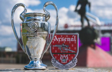 14 Haziran 2021 Londra, İngiltere. Arsenal F.C. Futbol kulübü amblemi ve UEFA Şampiyonlar Ligi Kupası modern bir stadyumun arka planına karşı..